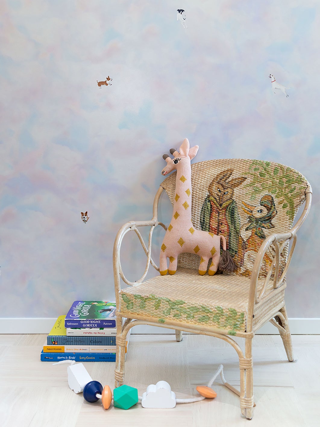 pale pink and blue wallpaper, baby chair and stuffed girafe