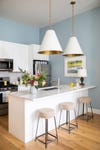 Painted Kitchen Island With Three Bar Stools and Large Pendant Lights