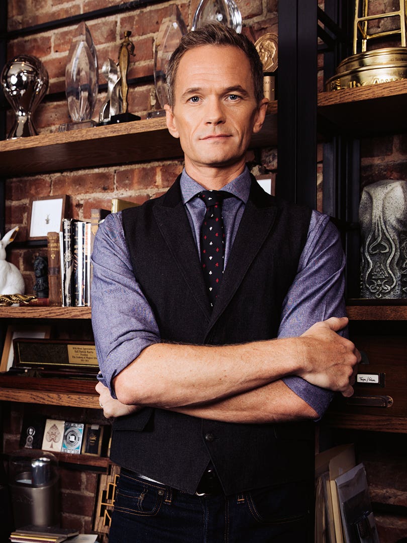 Neil Patrick Harris stands in front of bookcase