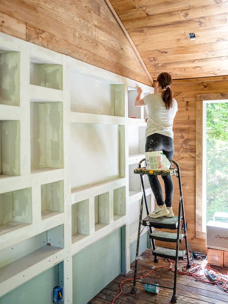 woman plastering bookcase