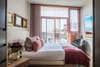 bright bedroom with large window and pink and red blanket