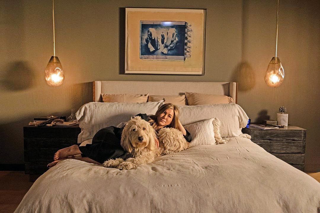 Jenifer Aniston lays on a bed with her dog in The Morning Show TV show