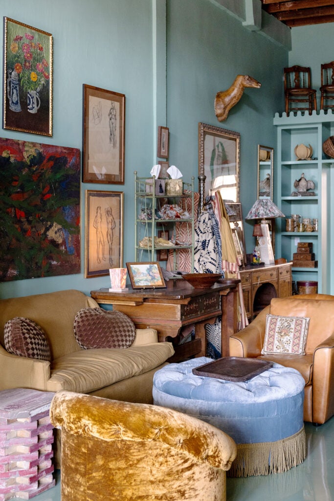Store corner, antique sofas and pouf, paintings frames hanging on the wall.