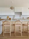 Light wood bar stools with blush cushion in white and wood kitchen