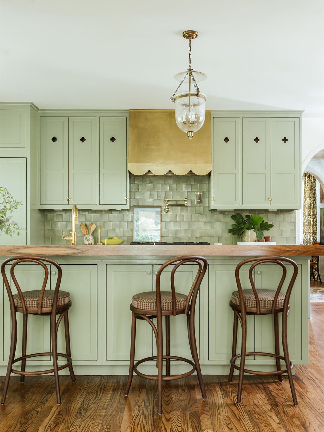 green kitchen cabinets and brass range hood