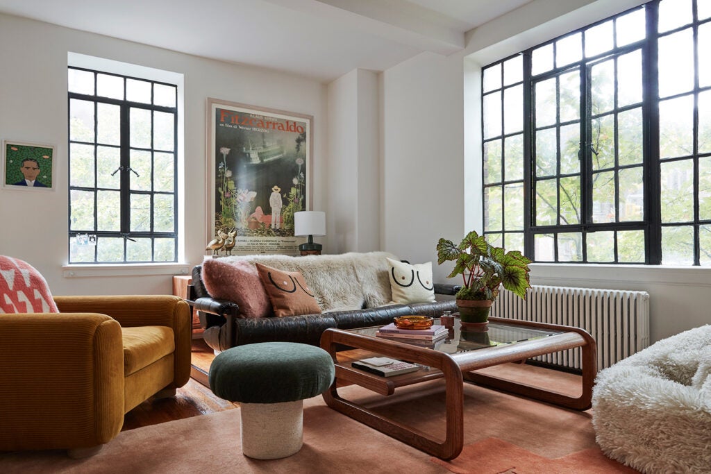 living-room shot, wooden and glass coffee table, pink rug and ochre corduroy armchair