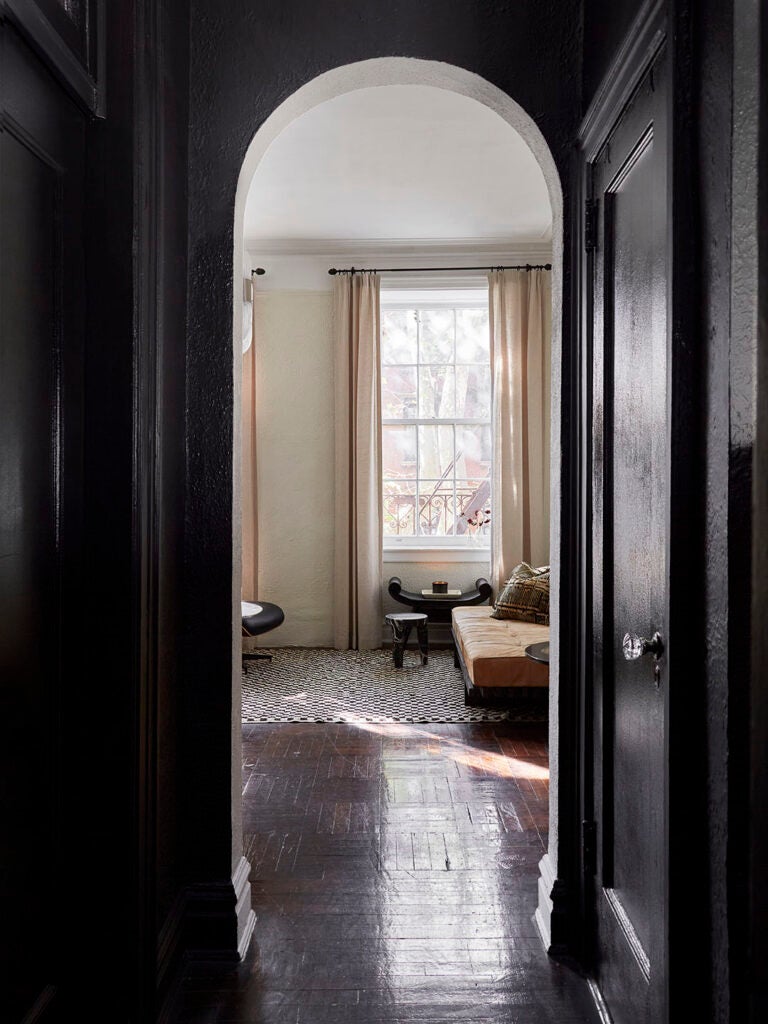 Black painted arched entryway looking into living room