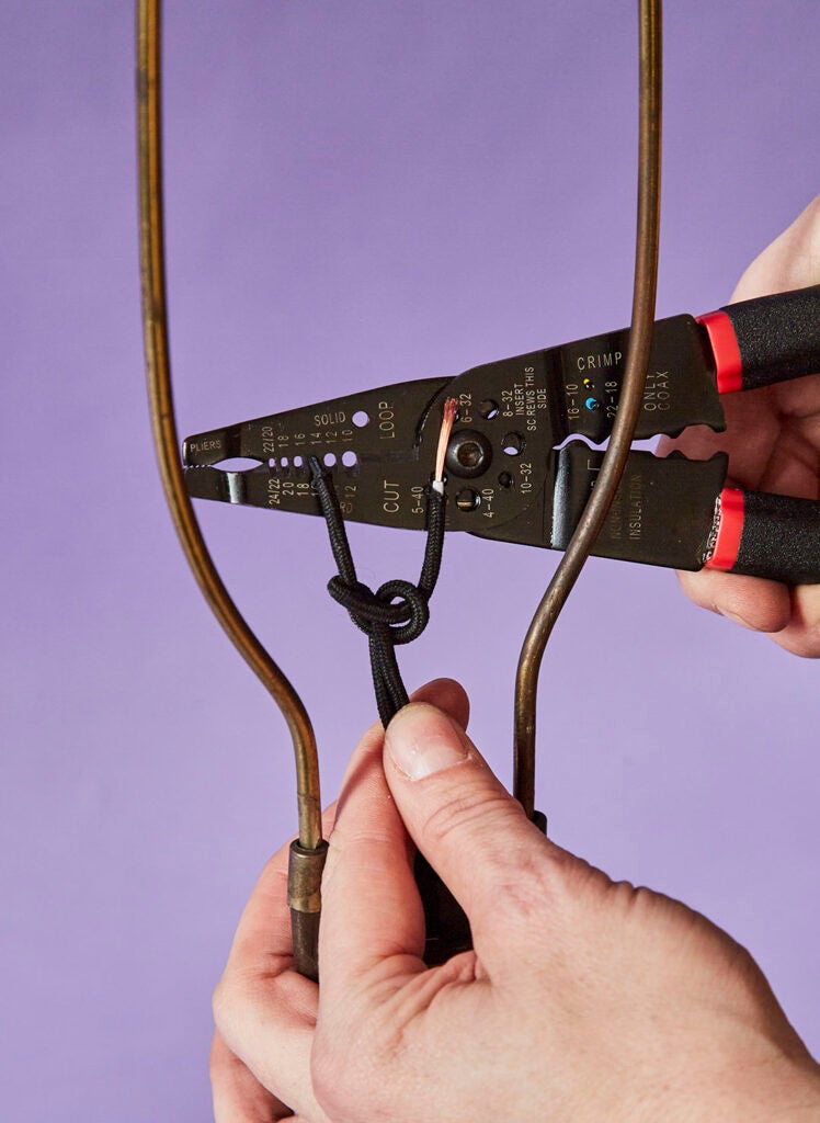 hand holding wirecutters to strip lamp wires