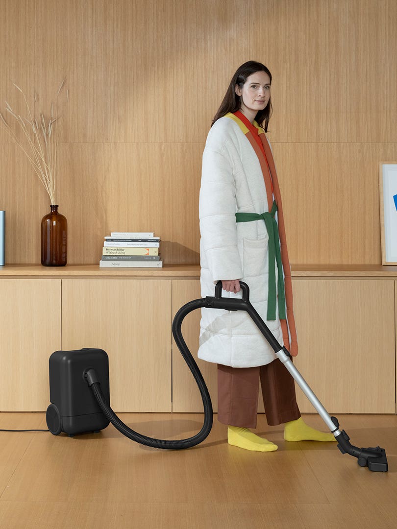 woman holding vacuum wearing housecoat
