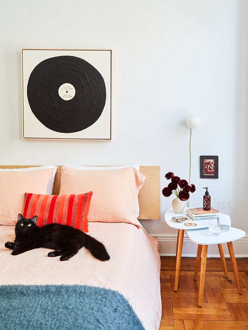 bedroom with pink bedding and black cat on bed