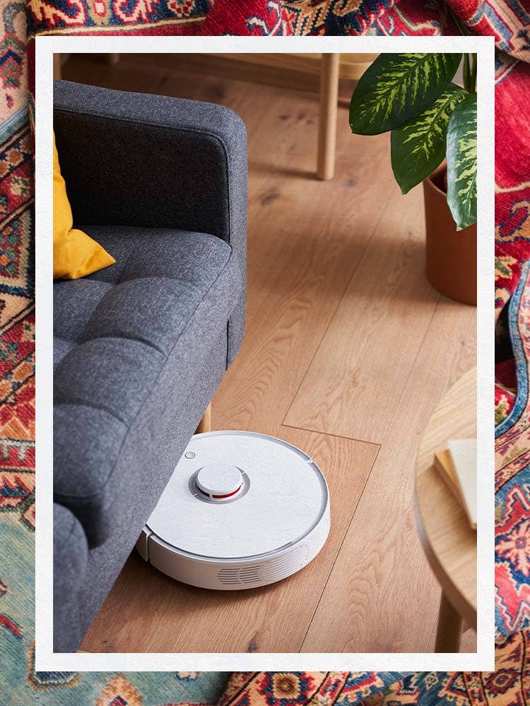 White Robot Vacuum Underneath Sofa on Wood Floors