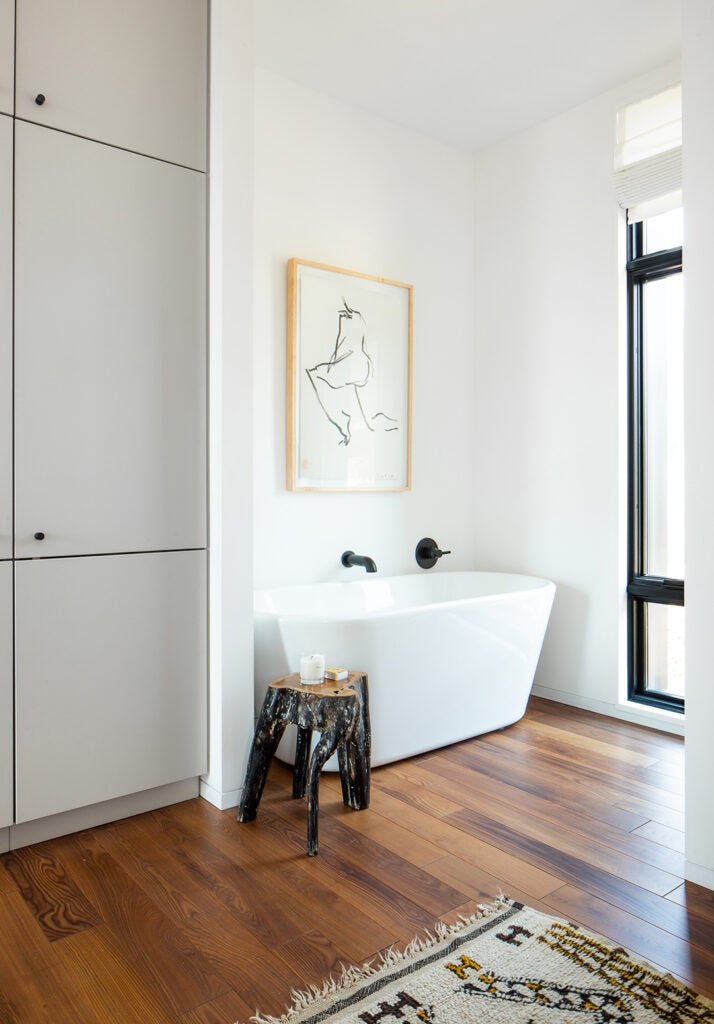 bathroom with white tub and artwork hanging overhead