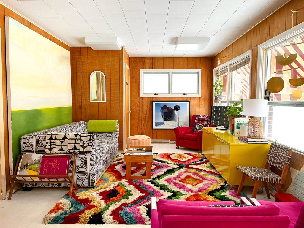 wood-paneled living room with rainbow rug