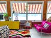view from colorful 1960s-style living room out windows with striped awning