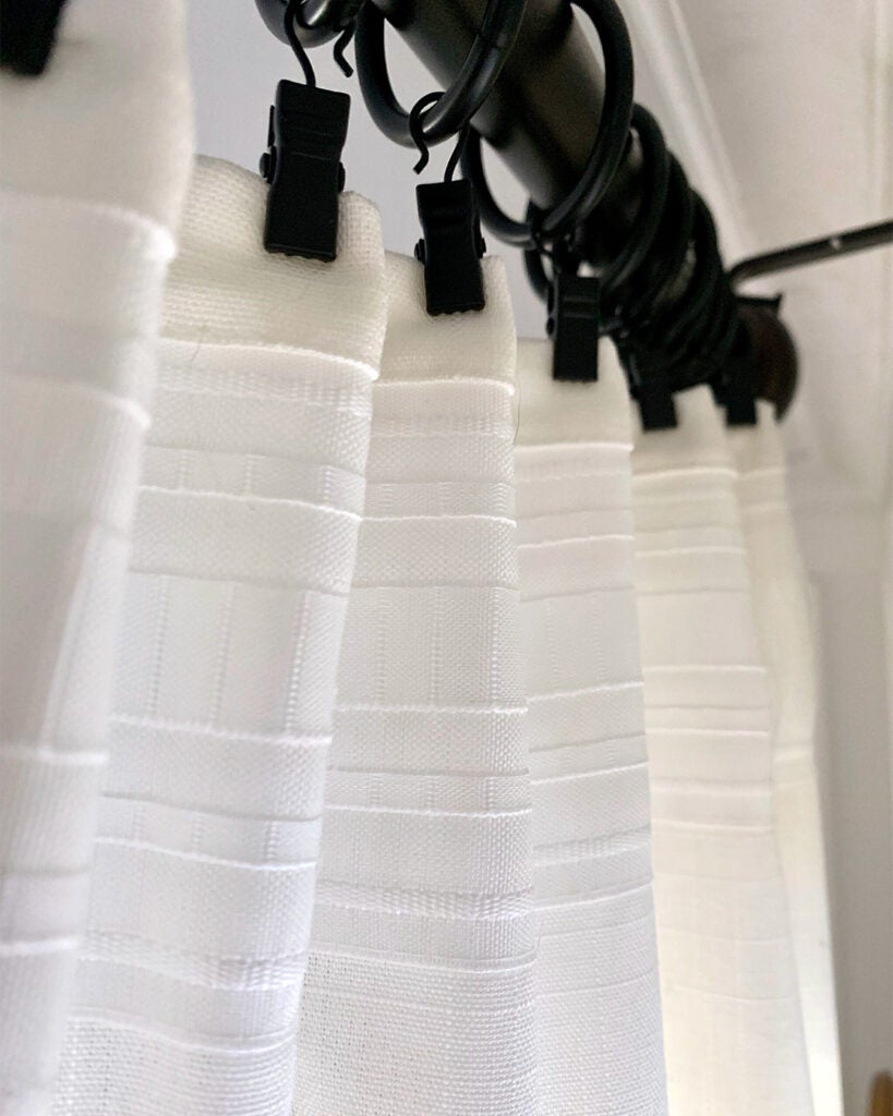 close-up of white curtains on black clip rings