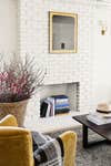 Yellow velvet chair placed near white exposed brick wall. 