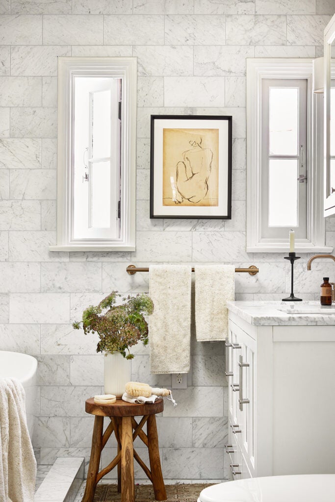 Wooden stool places in white marble tile bathroom.