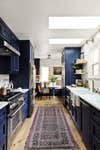 Kitchen with vintage rug and dark blue cabinetry.