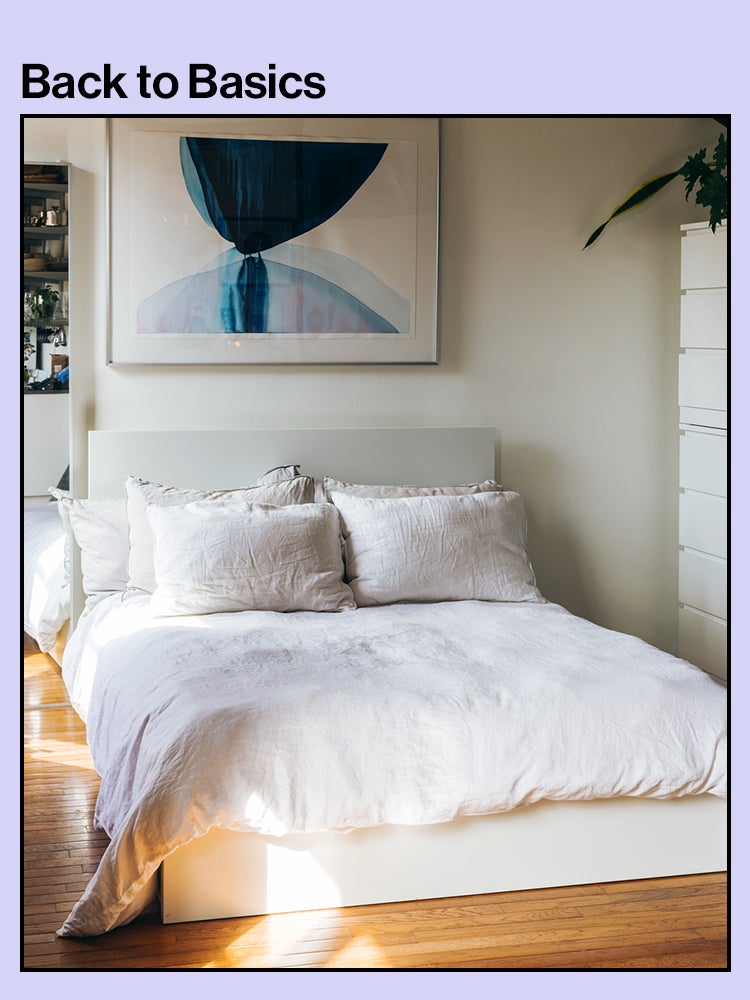 Bed with white comforter, linen pillowcases, and blue art