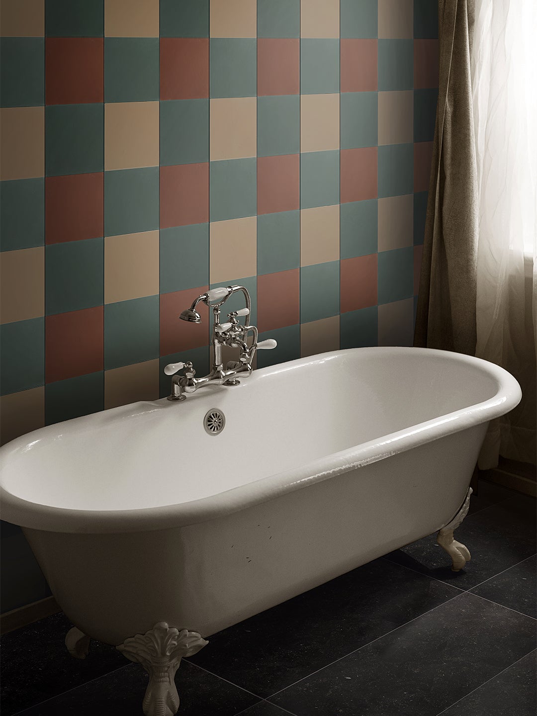 claw foot bathtub in front of tri-color tiled wall.