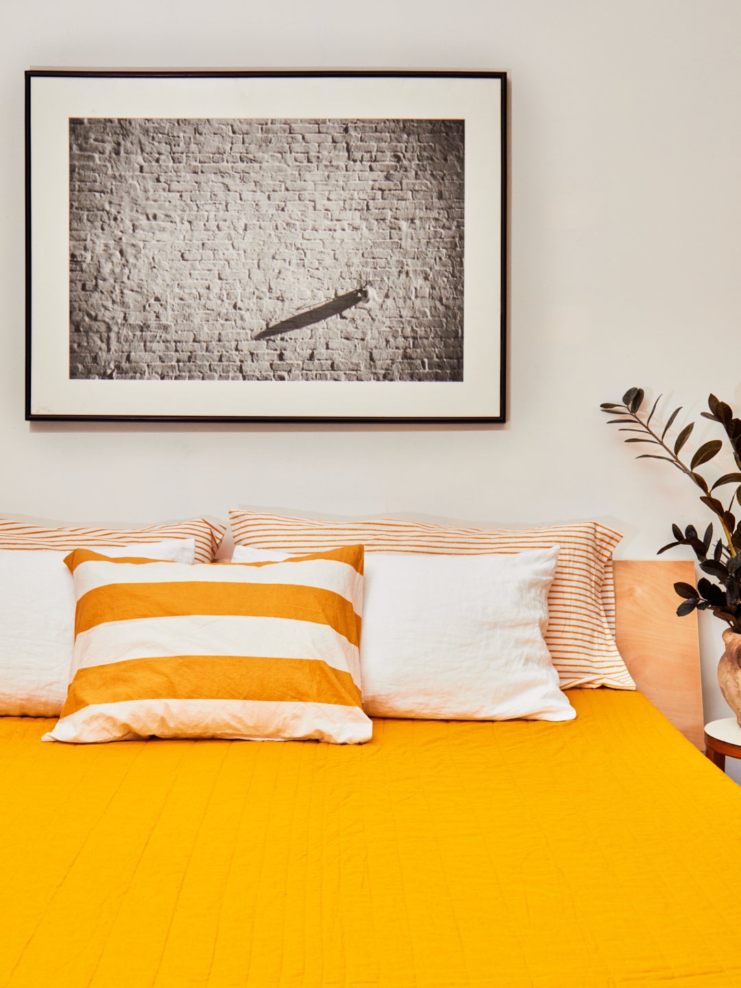 bed with orange duvet color and five striped and solid white pillows
