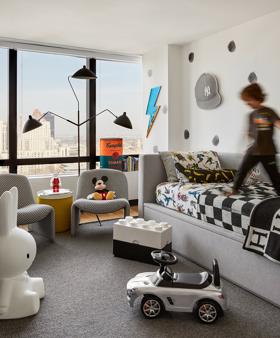 black and white kidâs room with boy jumping on twin bed