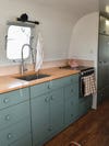 camper kitchen with pink backsplash and butcher block counters