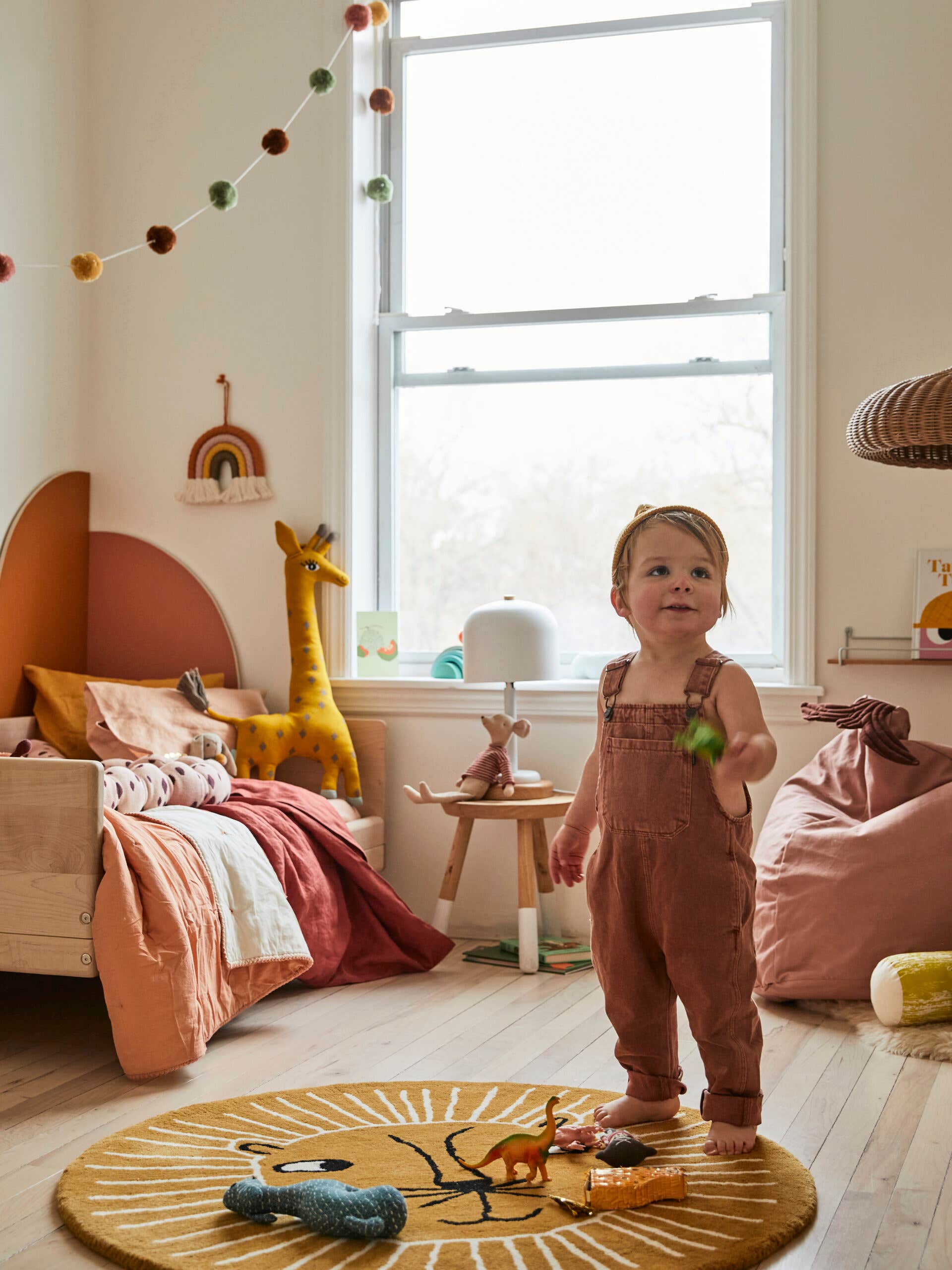 kid’s room with orange arches behind bed and toddler playing