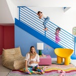 kids playing on blue metal staircase; mom sitting on rainbow rug