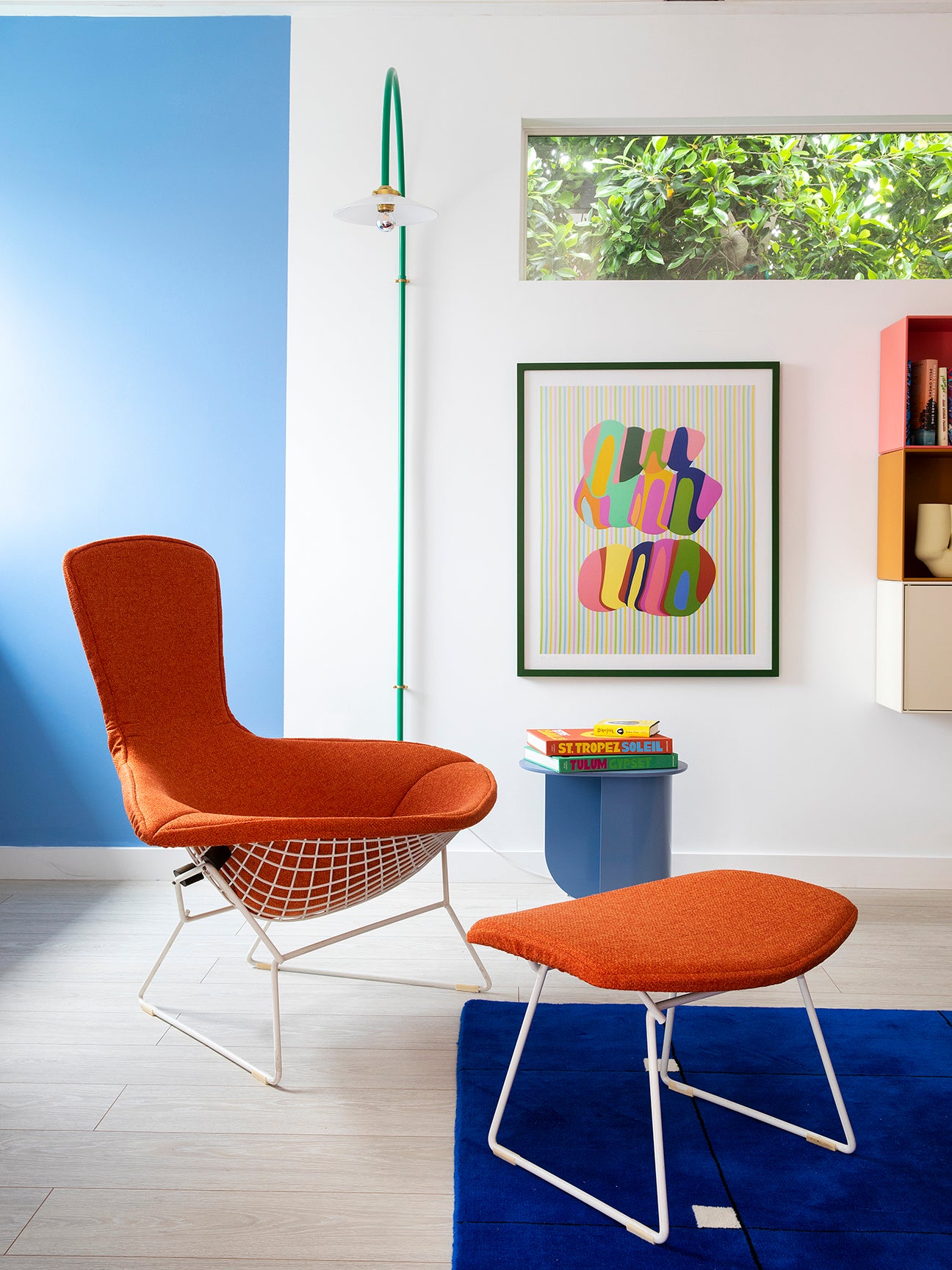 orange chair and ottoman with white wire base on cobalt rug