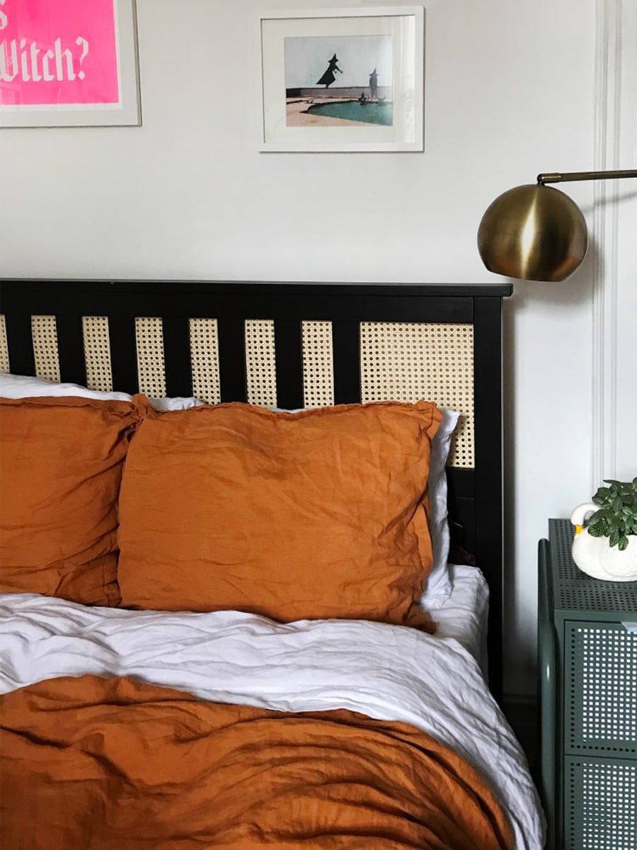 black bed frame with cane accents and orange bedding.
