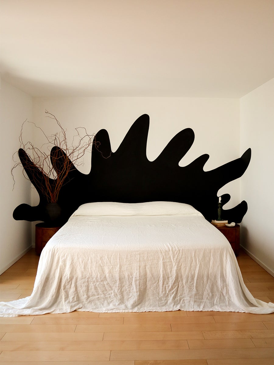 all white bed with black graphic painted headboard.