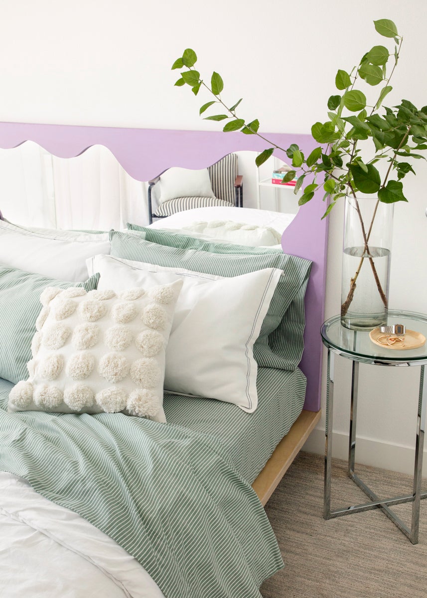 bed with purple mirror headboard and green striped bedding