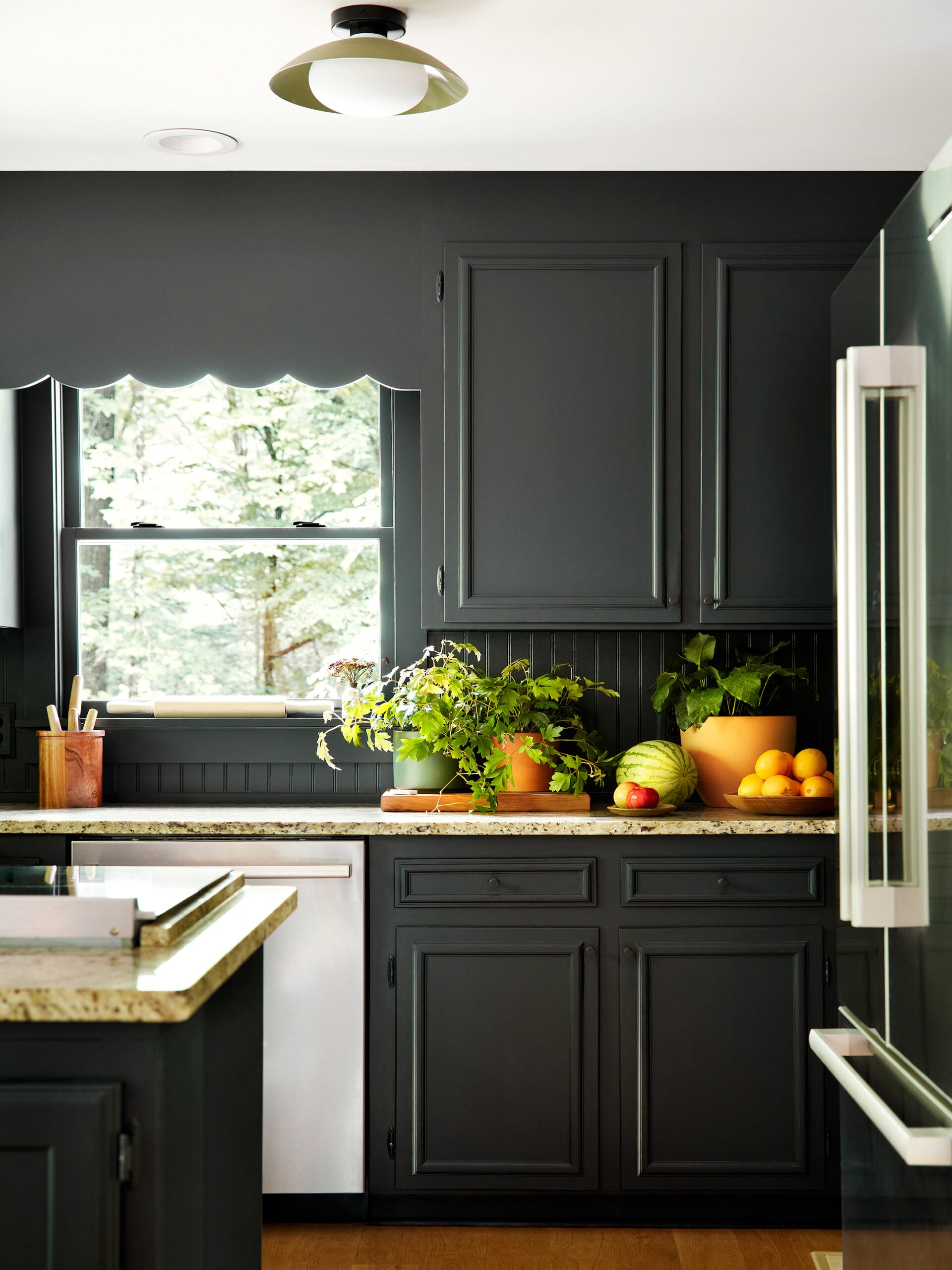 Black painted kitchen cabinets with scalloped detail by the window