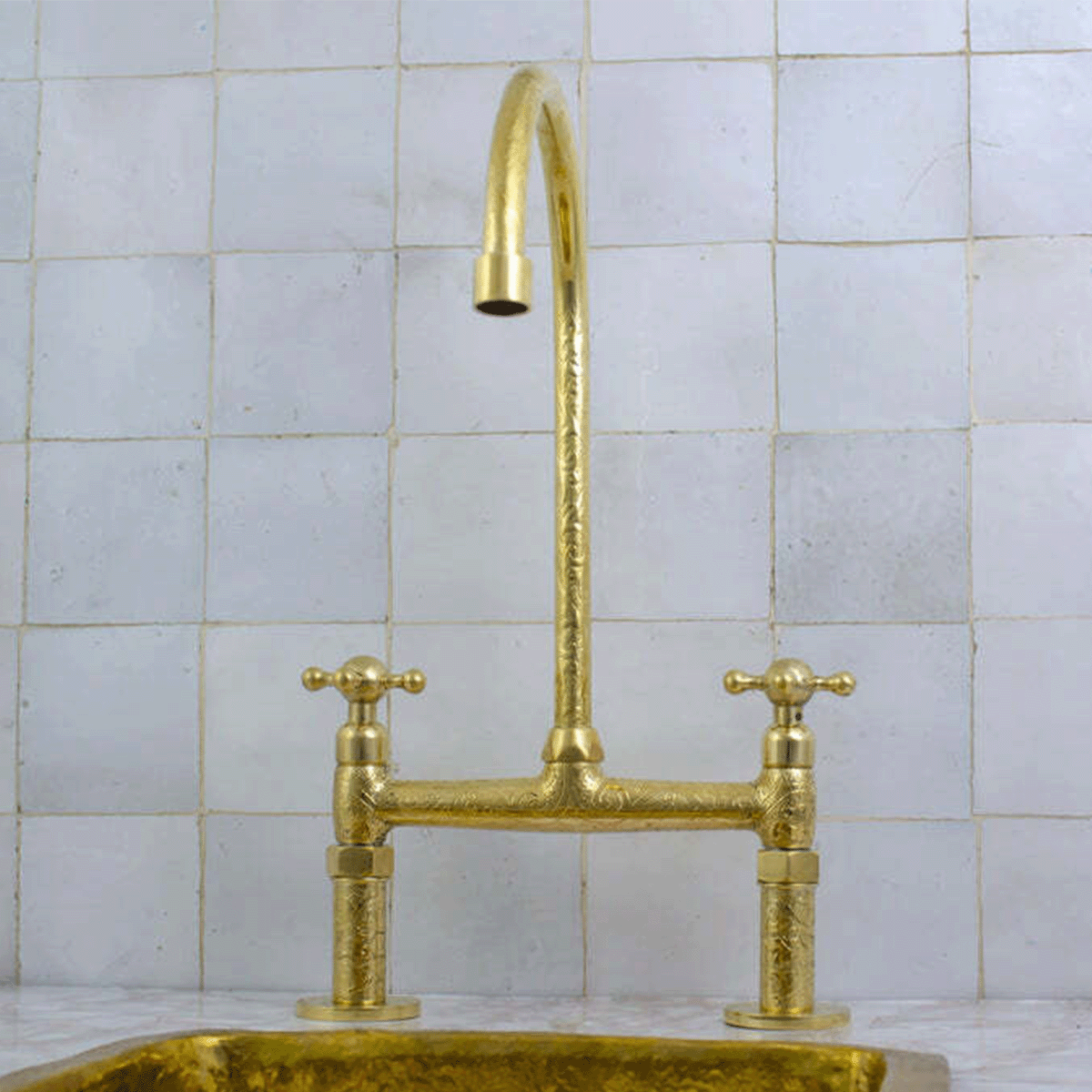 Gold faucet in front of white tile backsplash.