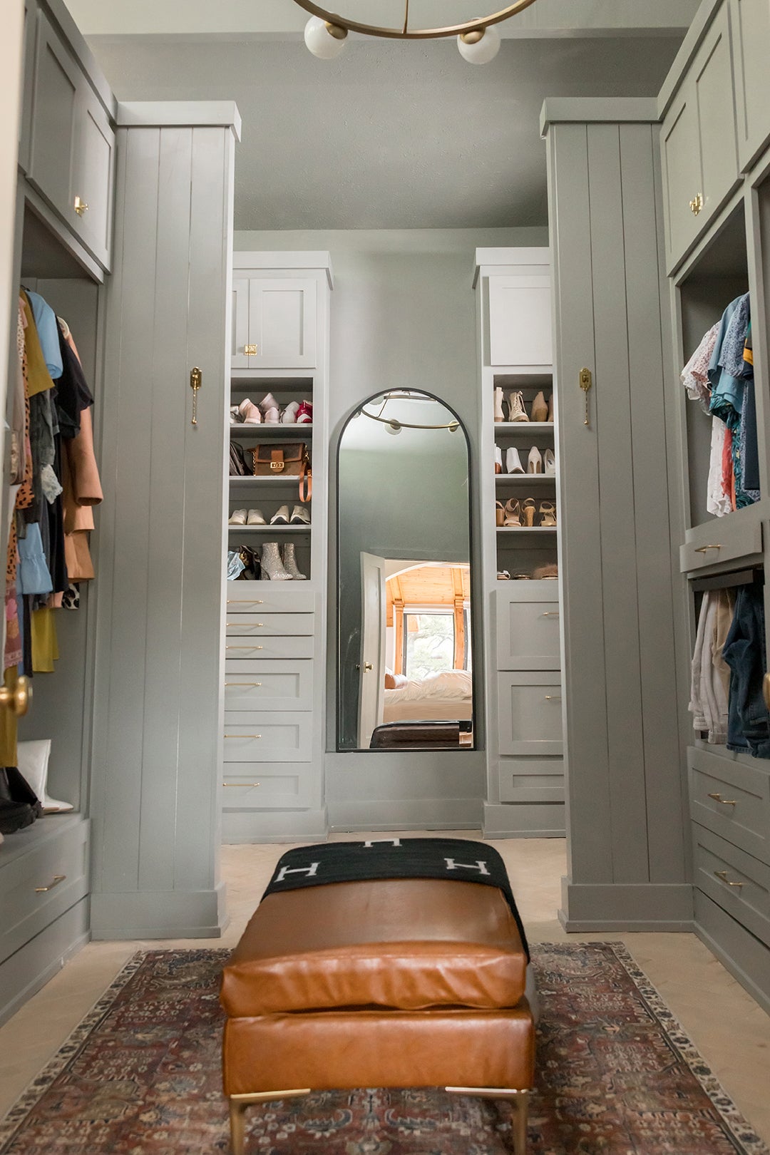 grey green closet with leather bench