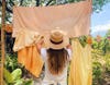 woman hanging naturally-dyed sheets on line