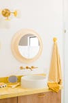 round butter yellow mirror above vanity