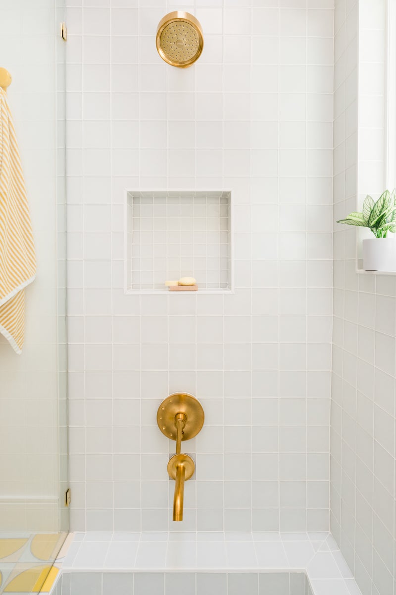 glass-tiled shower with brass fixtures