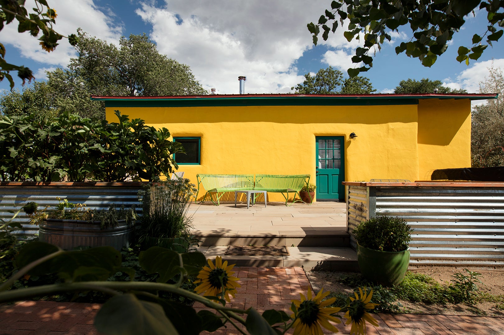 bright yellow adobe home exterior with green bench