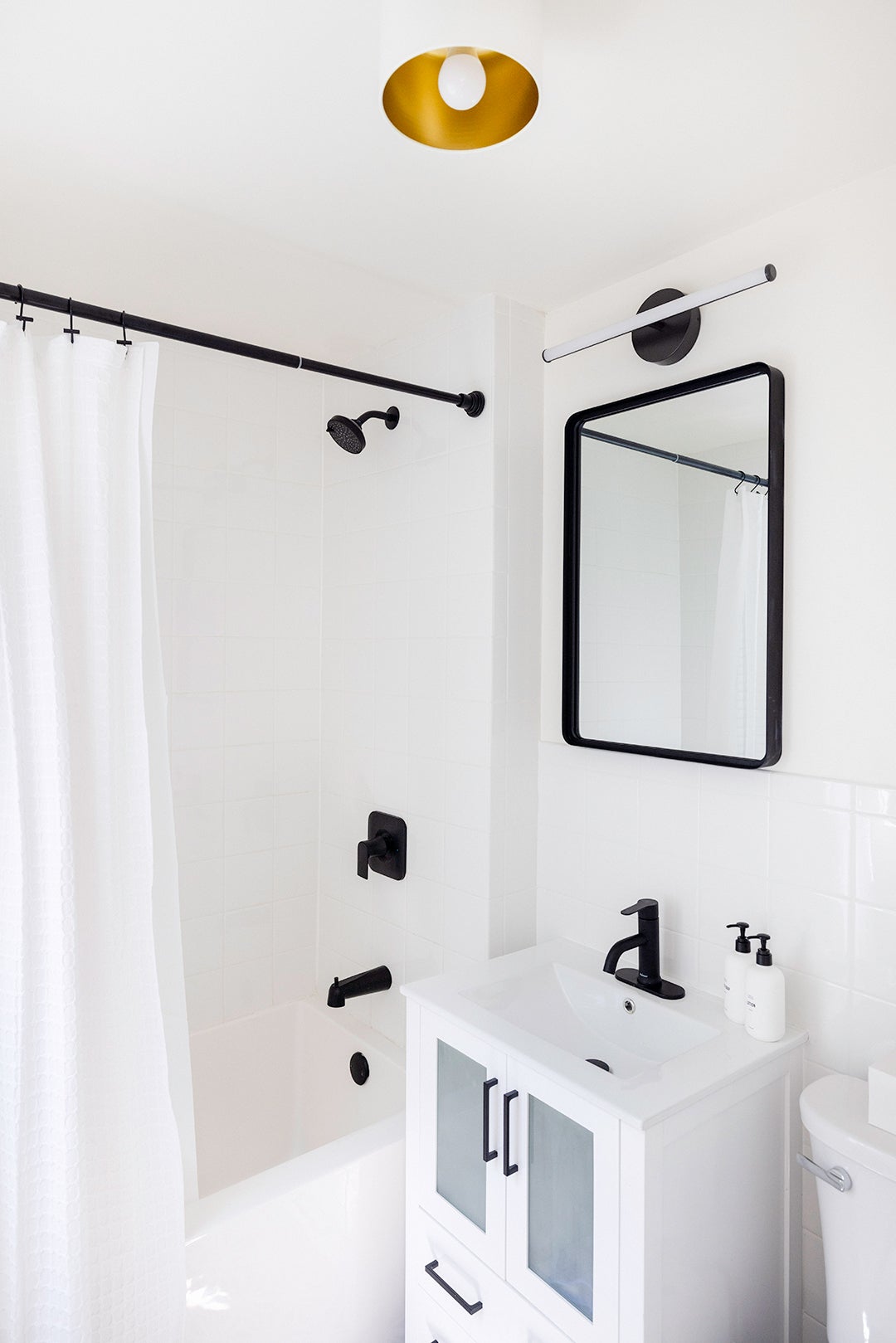 White bathroom with black vanity mirror and plumbing fixtures