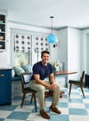 man in blue shirt posing in a dining chair in a kitchen
