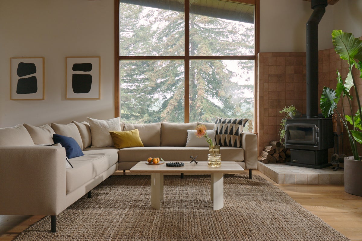 Large, white sectional couch in living room with stove fireplace and the city table in bone 