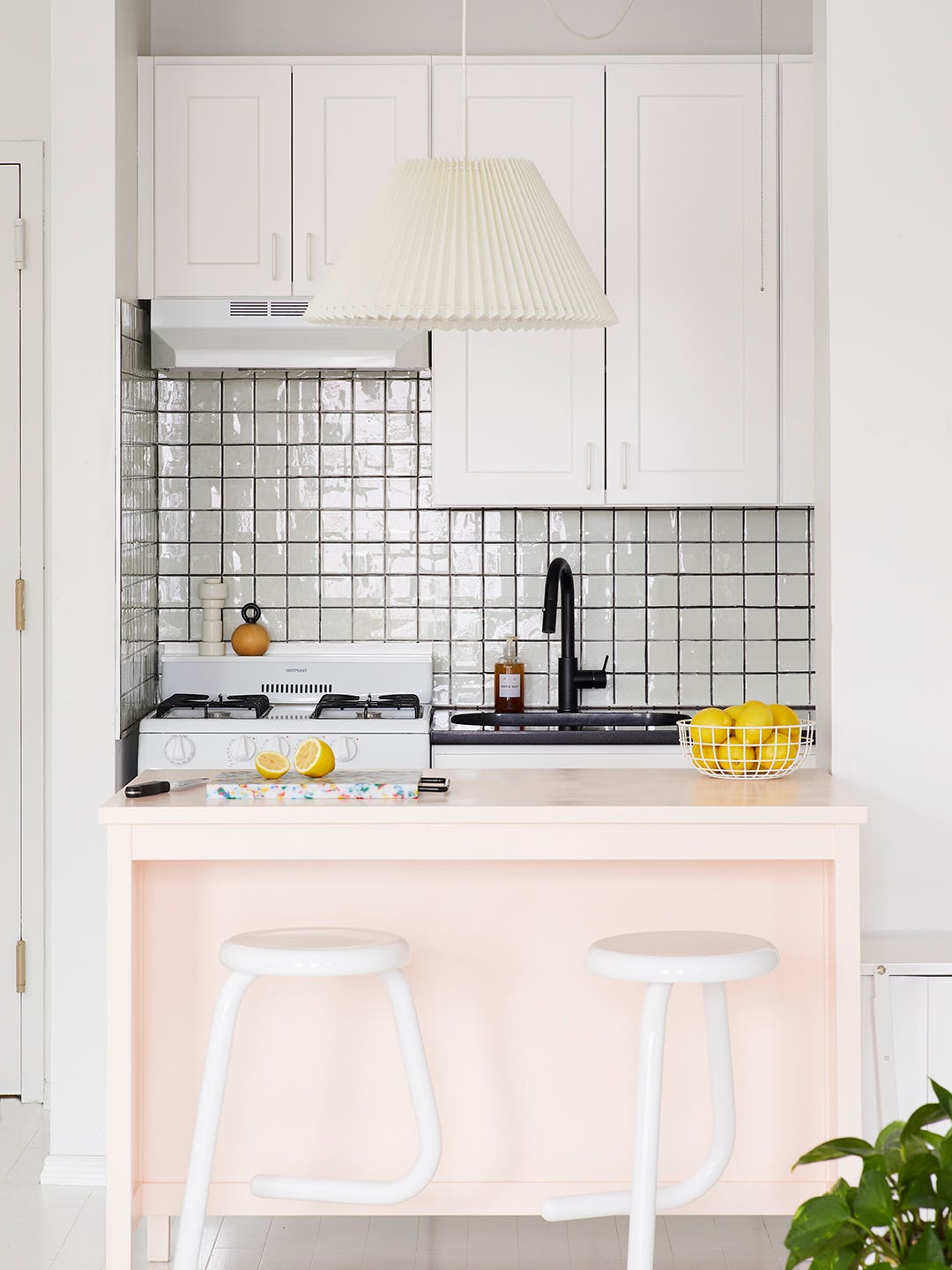 pink kitchen island with white cabinets and peel-and-stick backsplash