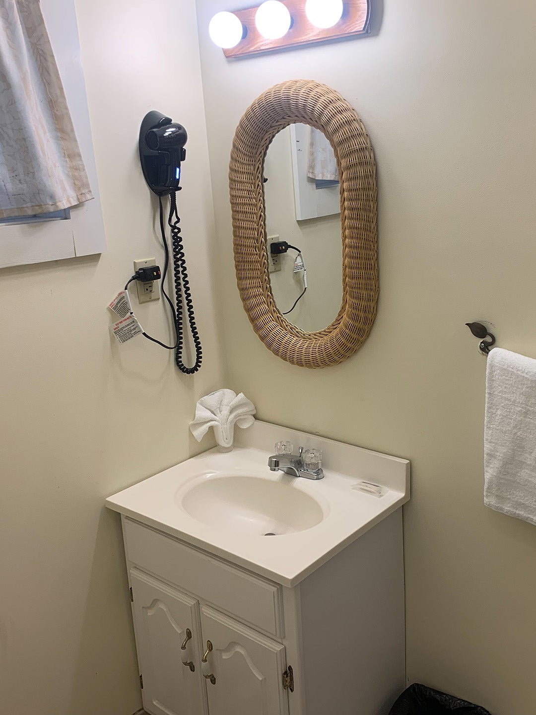 Dark small bathroom with rattan mirror