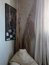 A bedroom corner, adorned with a white bean bag chair, a painting, and tall dried branches.