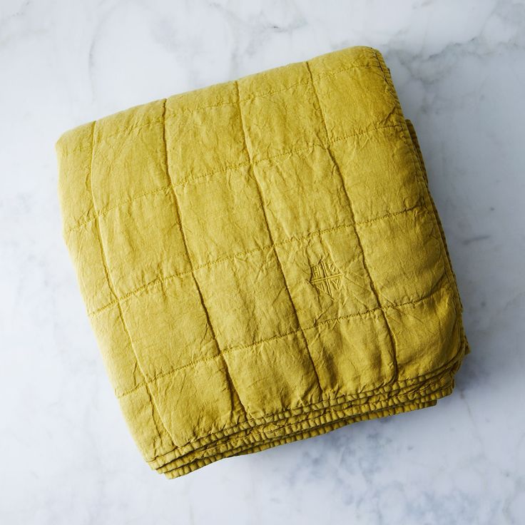 Mustard quilt folded on a marble surface.