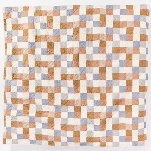 Square mosaic neutral toned quilt flat against a white background.