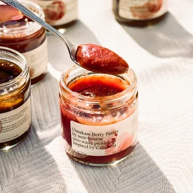 Omakase Berry Butter spooned amidst open jars of berry butter on a tablecloth.