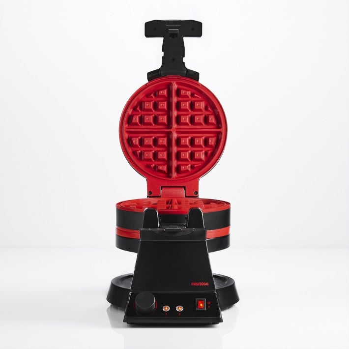 Red and black waffle iron in the middle of a white background.